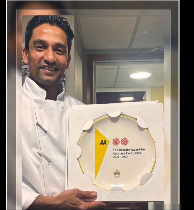 Chef Rasel holding an AA Rosette for Culinary Excellence plaque